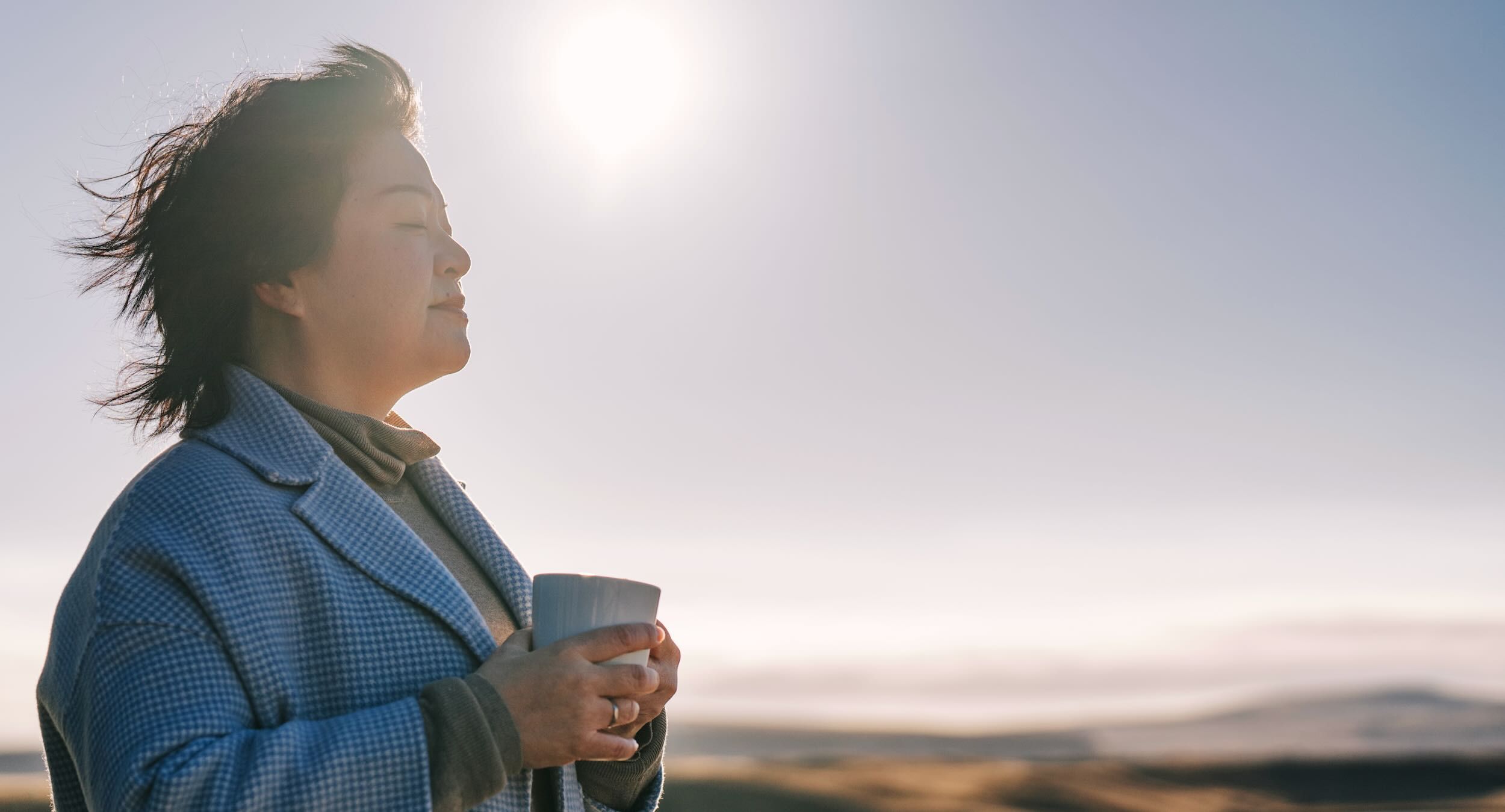 A woman enjoys a cup of coffee outdoors