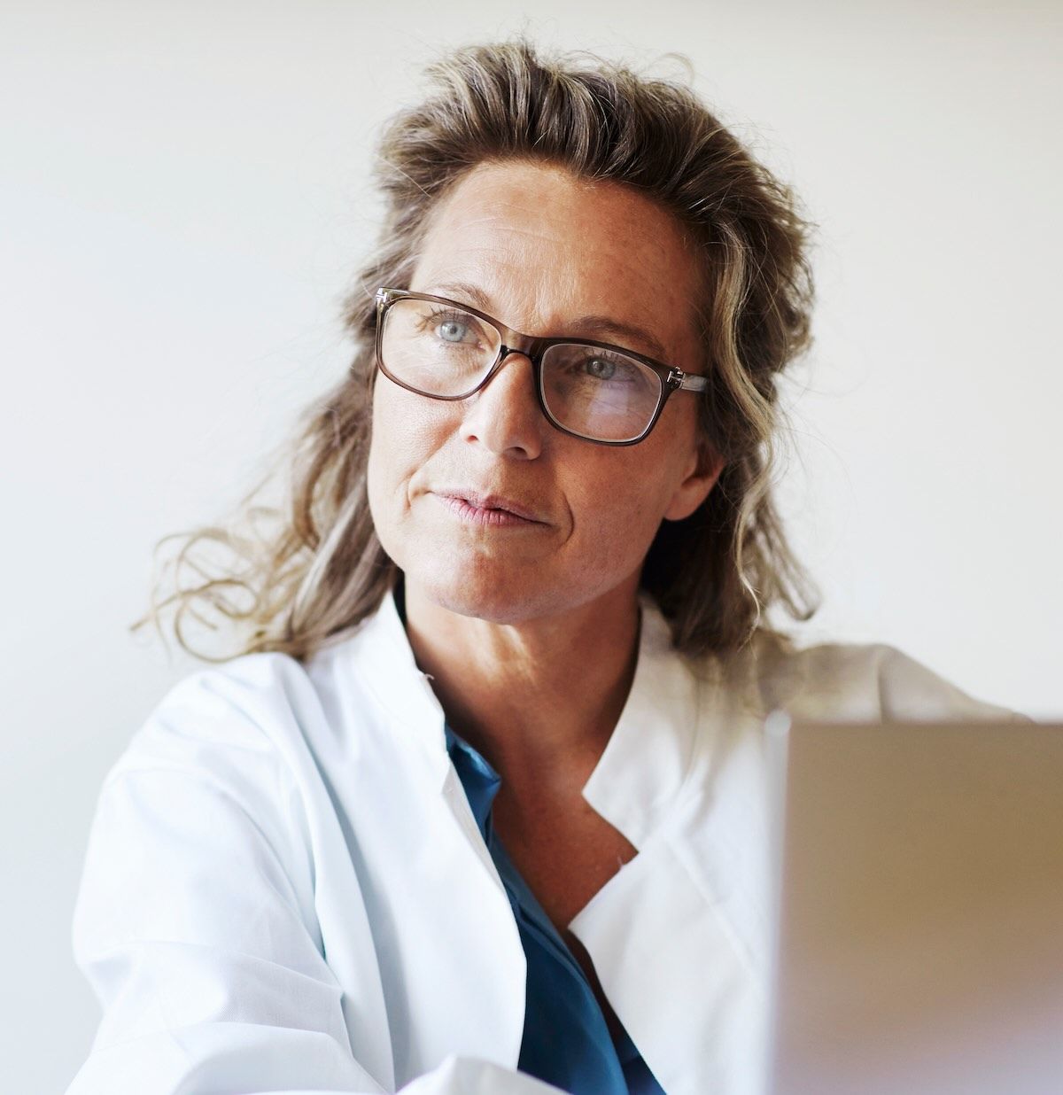 A doctor speaks with a patient while working on a laptop