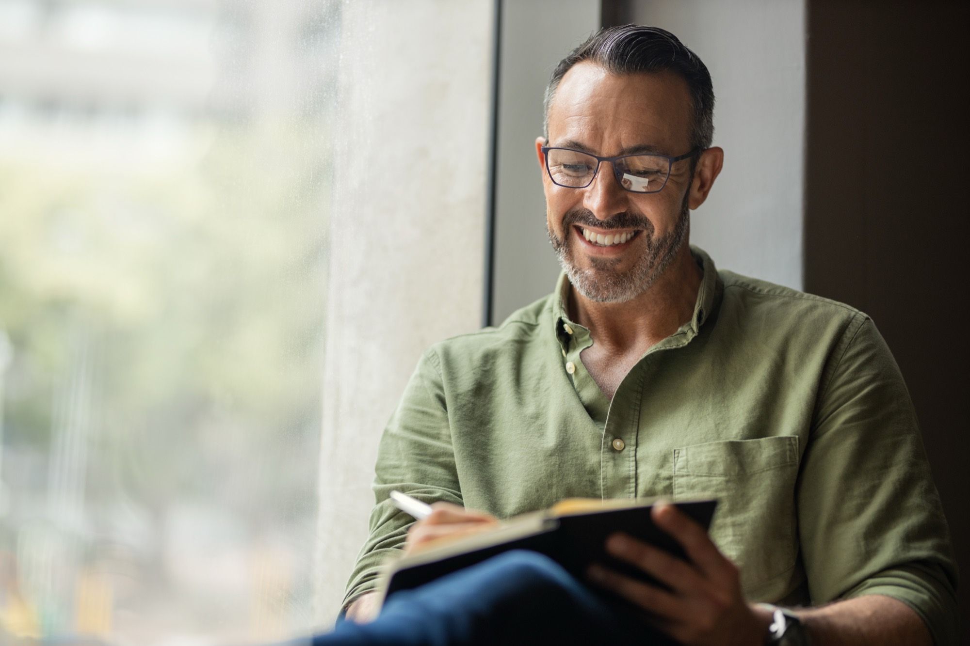 A healthcare provider smiling while writing in a notebook