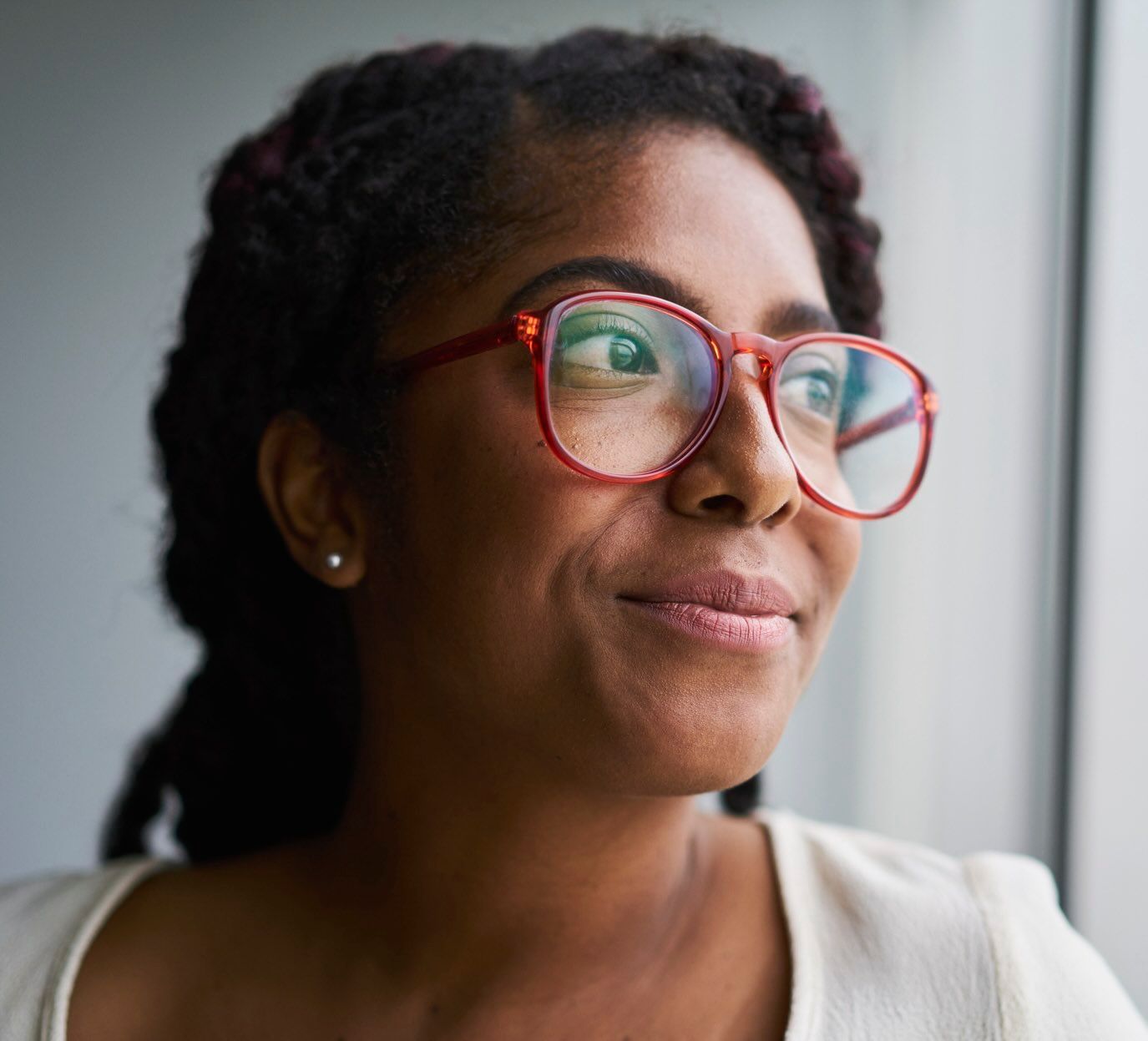 A woman looks out a window with a slight smile