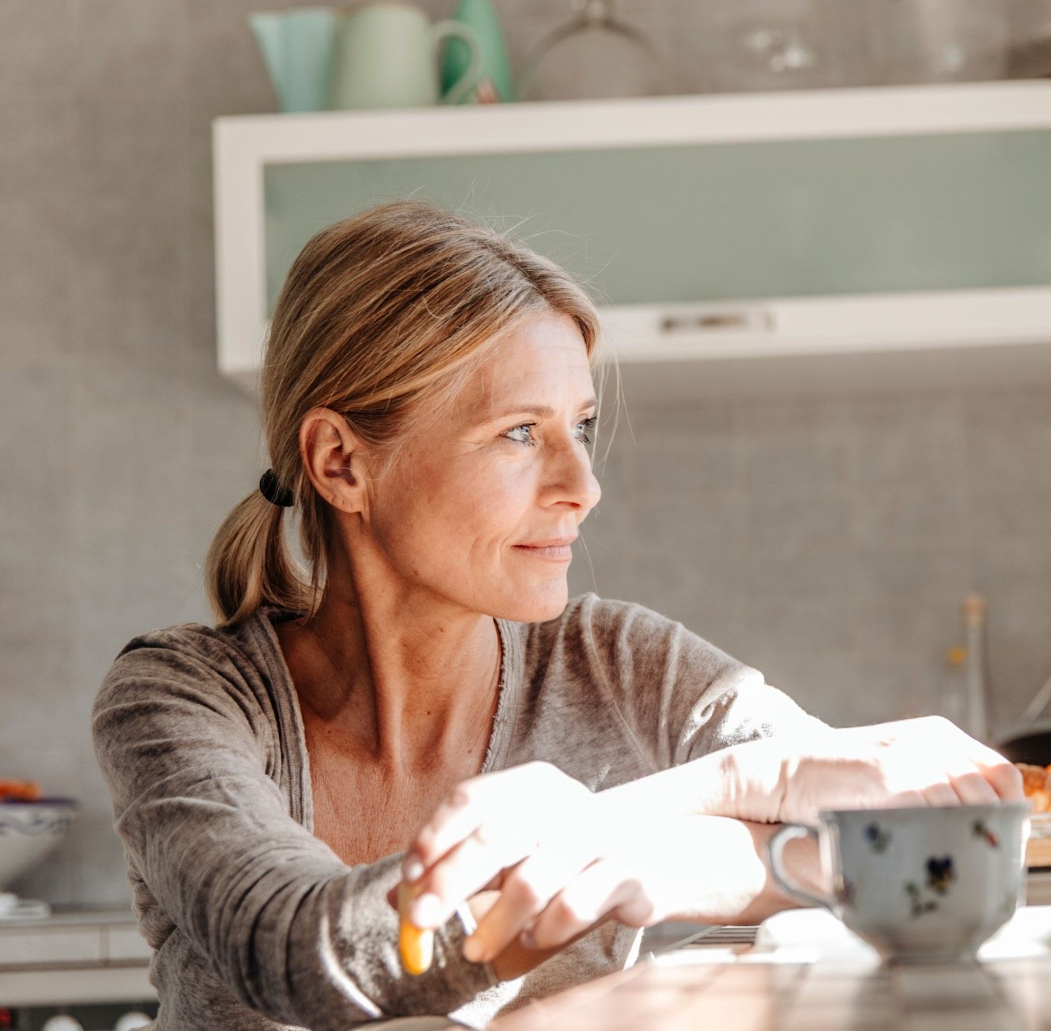 A woman gazes out of a window smiling slightly