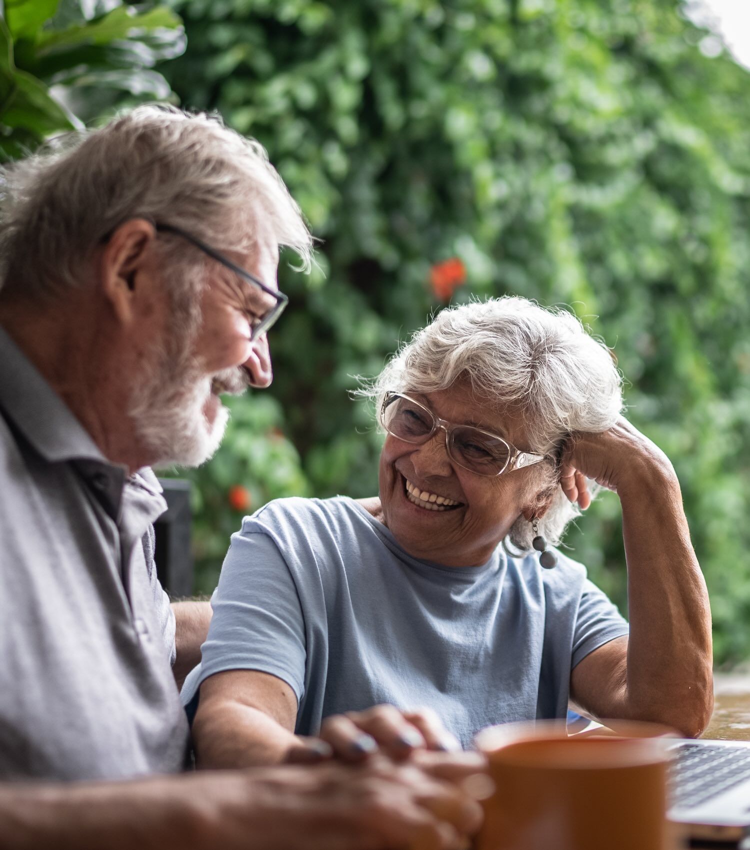 A man and woman laugh while sitting at a table together