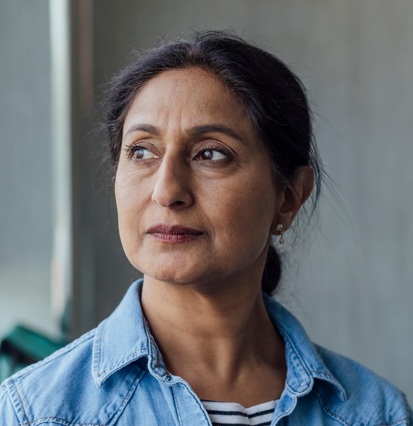 A woman looks out a sunny window