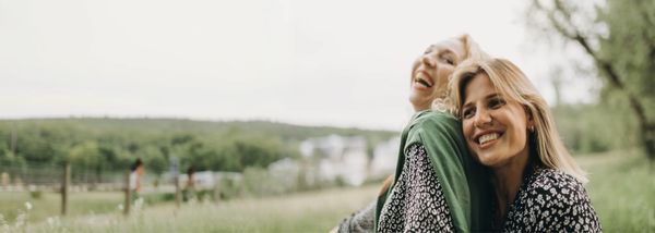 Two women laughing together in a field
